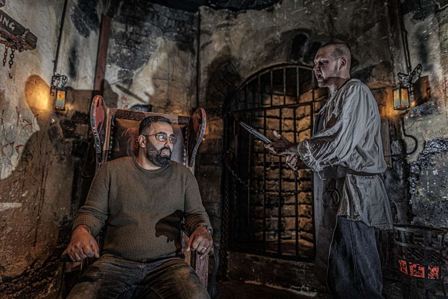 Foto aus dem Hamburg Dungeon, ein Besucher sitzt auf einem Folterstuhl und wird von einem Darsteller mit einer Zange bedroht