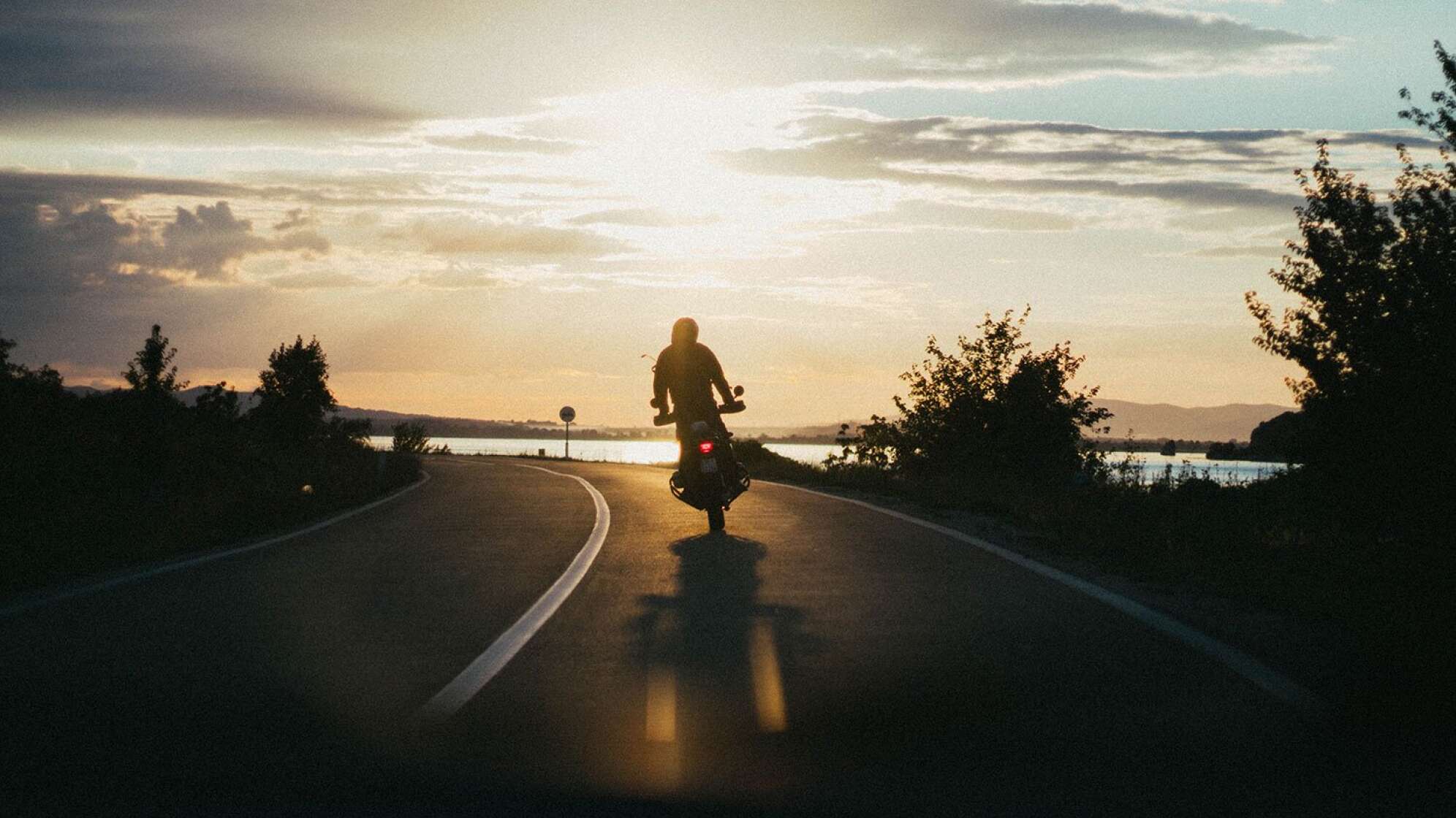 Motorradfahrer fährt in Sonnenuntergang
