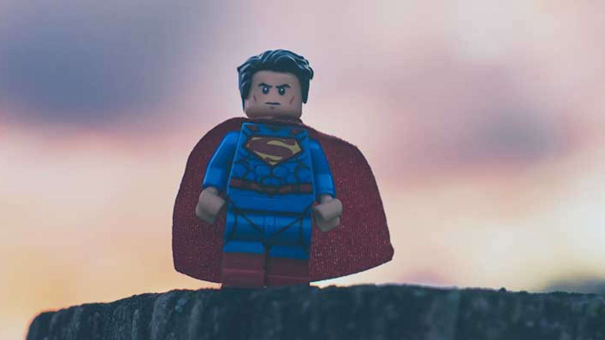 Lego Superman auf einem Baumstamm mit Umhang