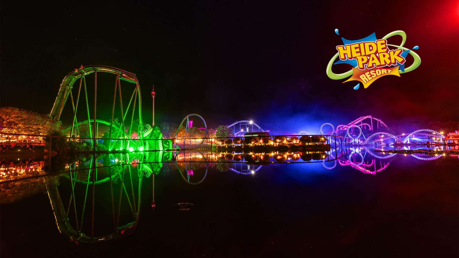 Skyline des Heide Park Resorts im Dunkeln, die Achterbahnen sind in verschiedenen Neon-Lichtern angestrahlt