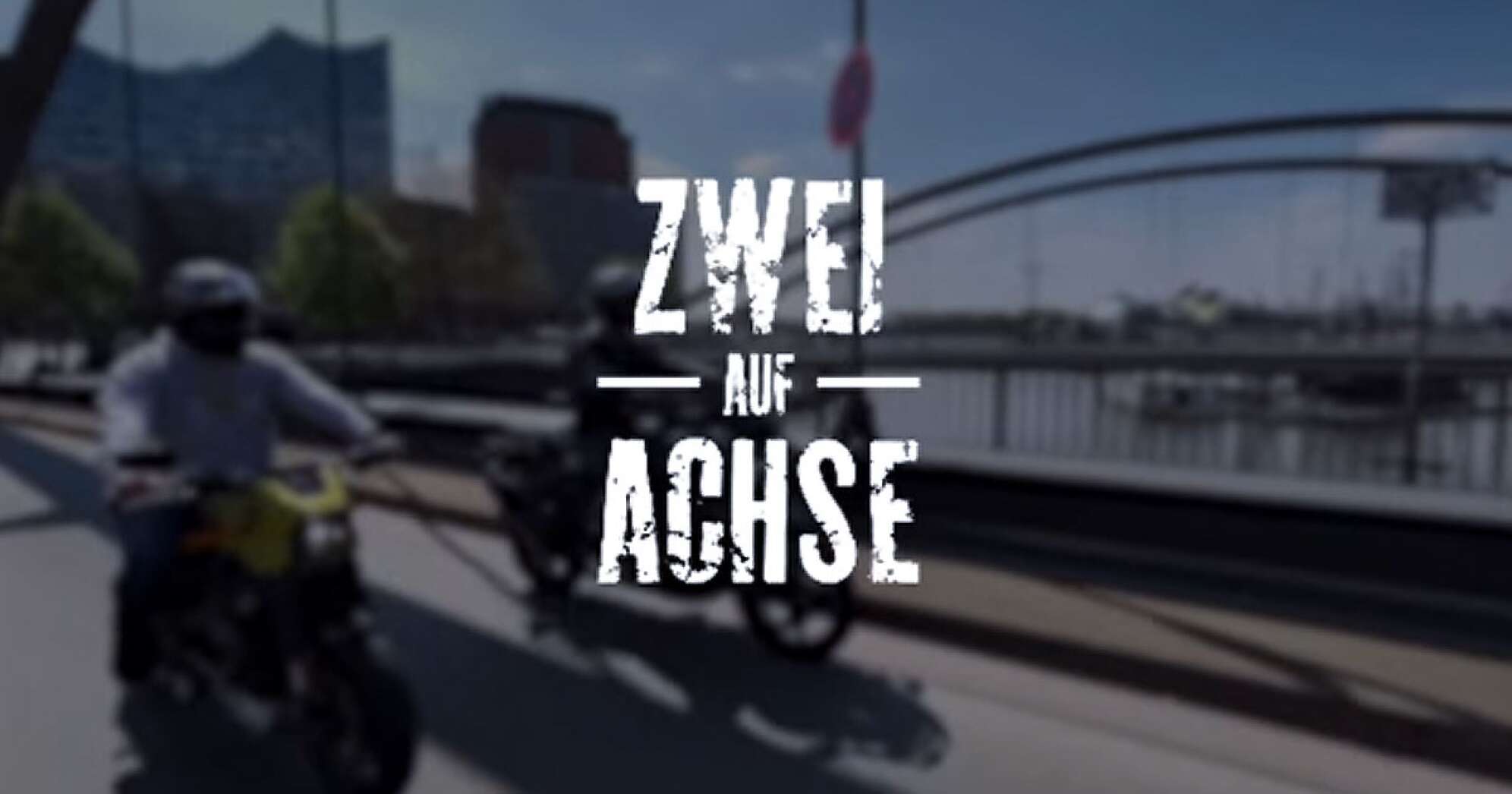 das Titelbild des Video Blogs "Zwei auf Achse" - zwei Motorradfahrer auf einer Brücke in der Speicherstadt vor der Kulisse des Hamburger Hafens mit der Elbphilharmonie