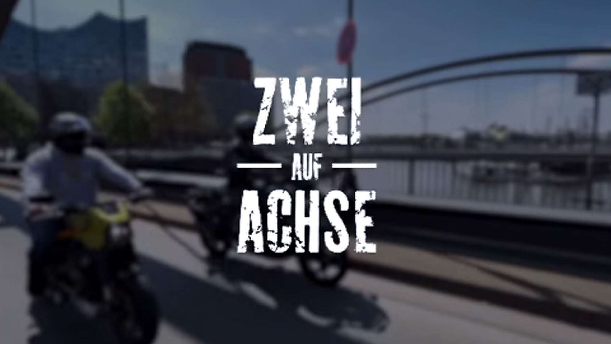 das Titelbild des Video Blogs "Zwei auf Achse" - zwei Motorradfahrer auf einer Brücke in der Speicherstadt vor der Kulisse des Hamburger Hafens mit der Elbphilharmonie