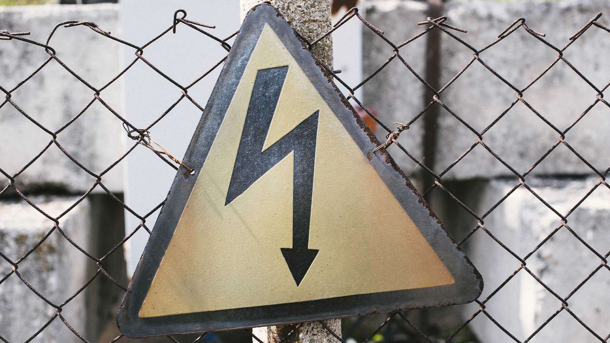 Warnschild vor Elektrizität (Blitz) an einem Zaun