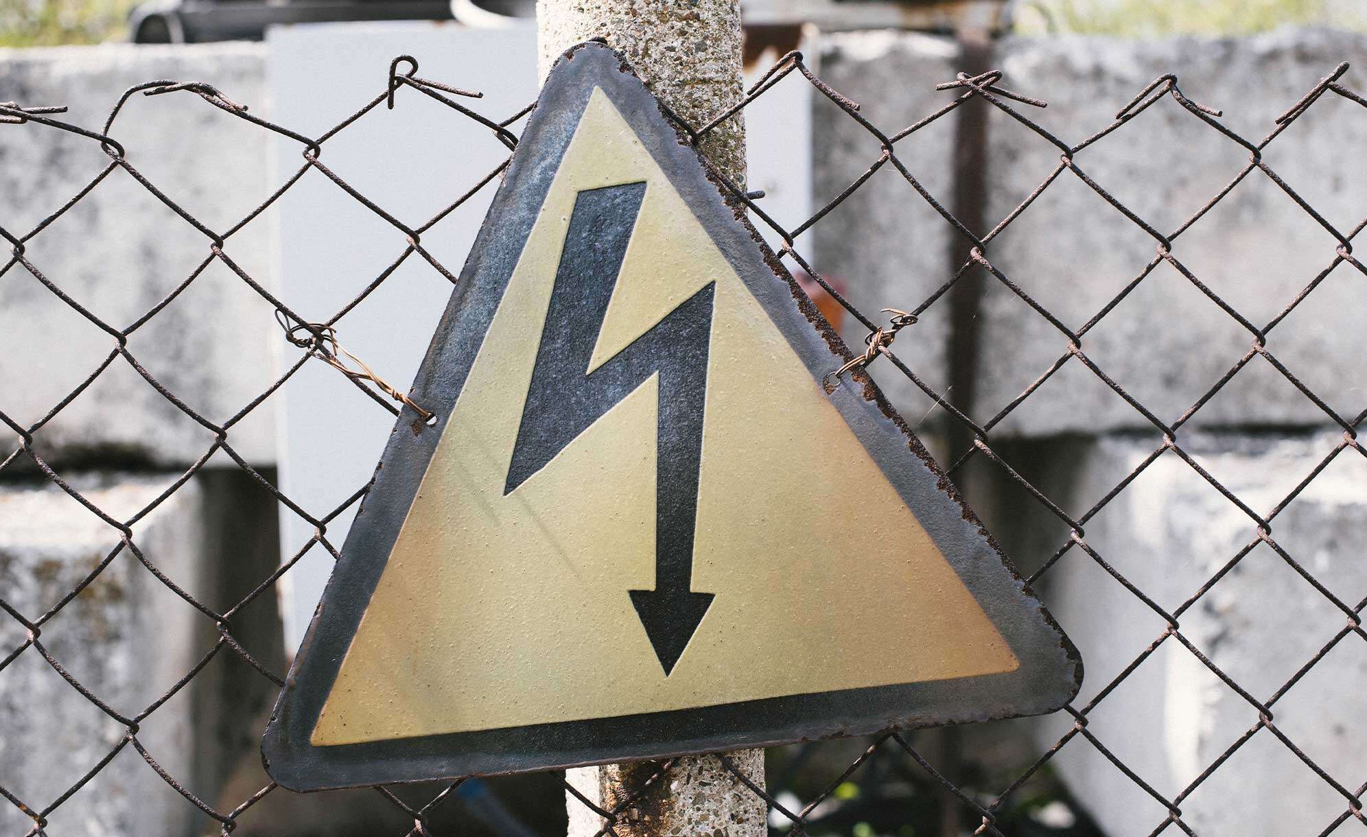 Warnschild vor Elektrizität (Blitz) an einem Zaun