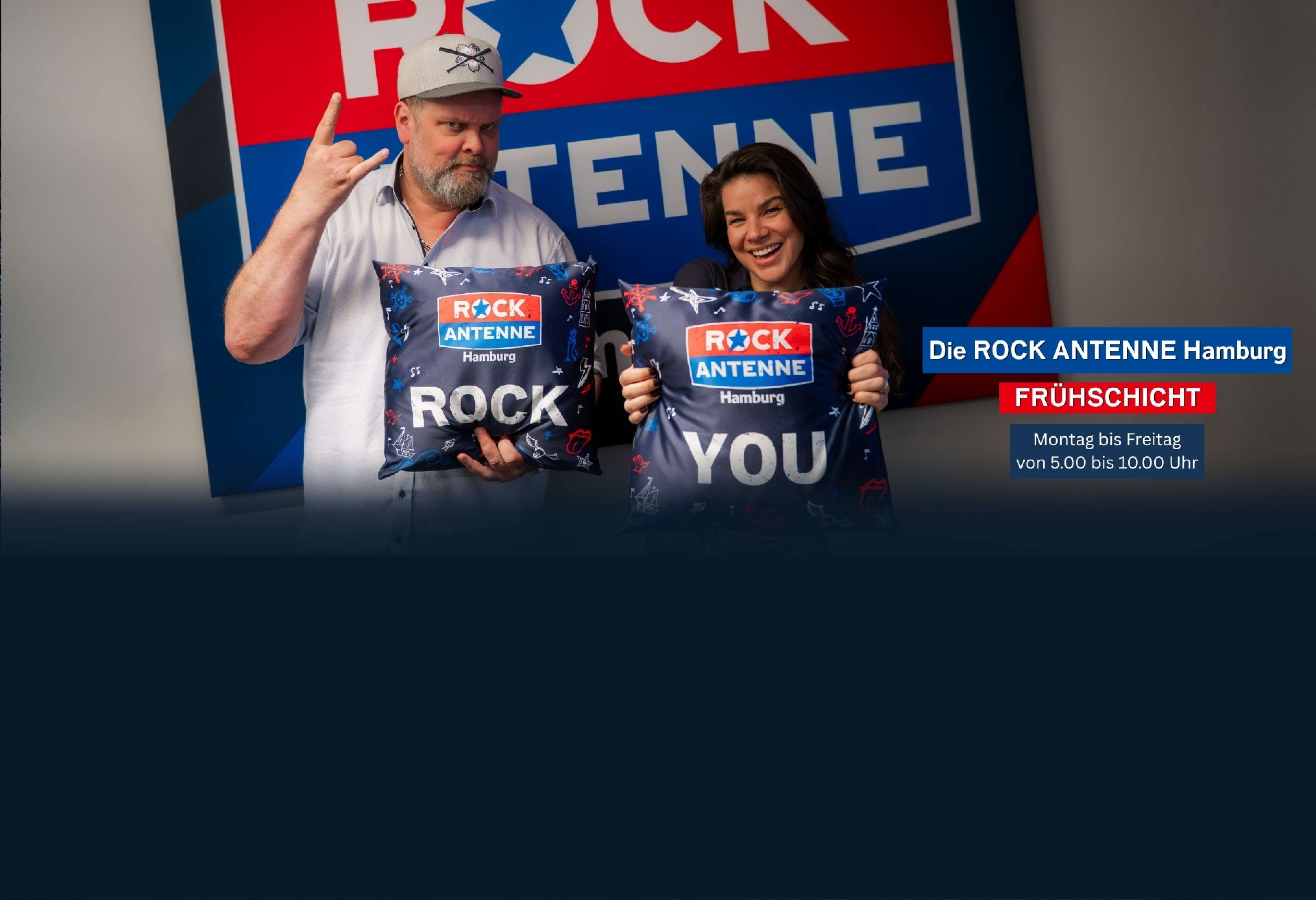 Morningshow-Moderatoren Alex Schmidt und Lilly Roberts von ROCK ANTENNE Hamburg vor RAHH Leinwand mit RAHH-Kissen "Rock you"