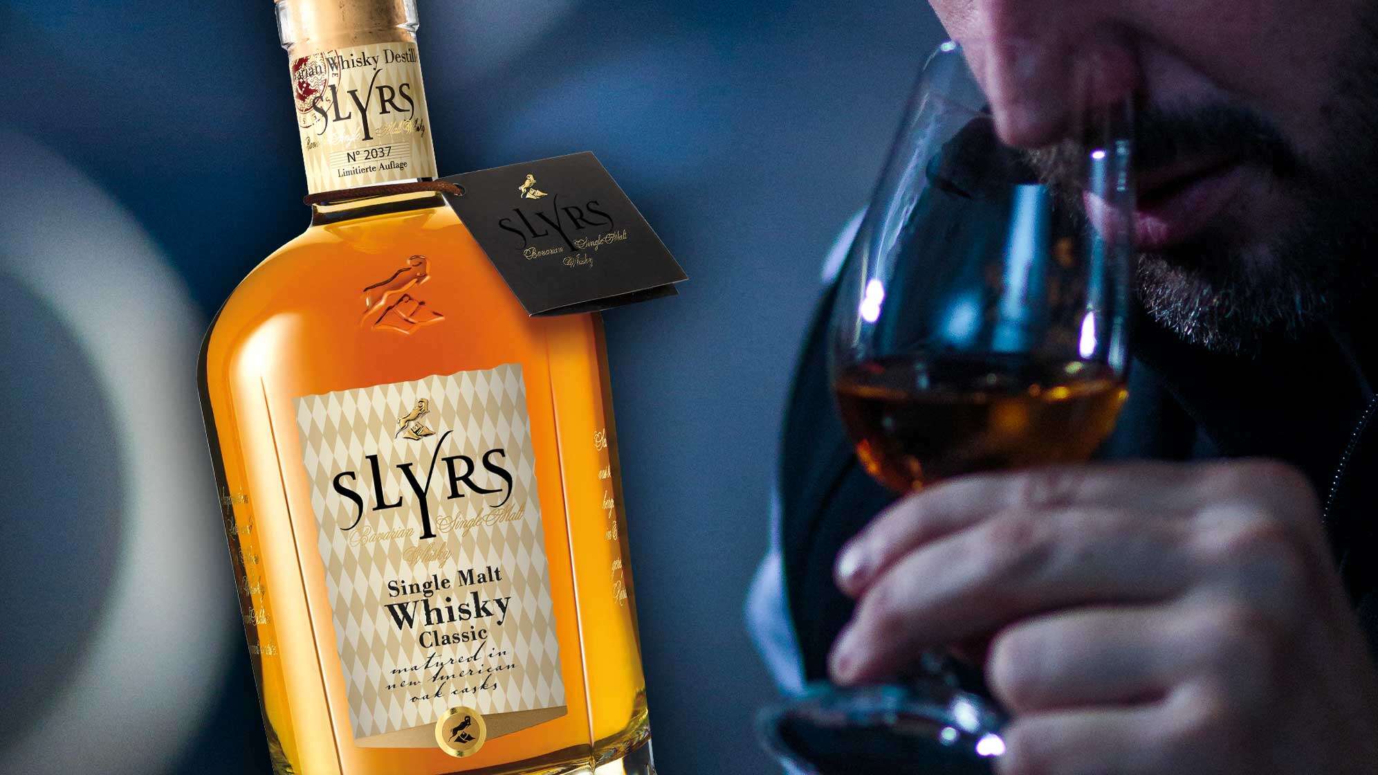 Eine Flasche Slyrs Whiskey und ein Mann, der ein Glas davon verkostet.