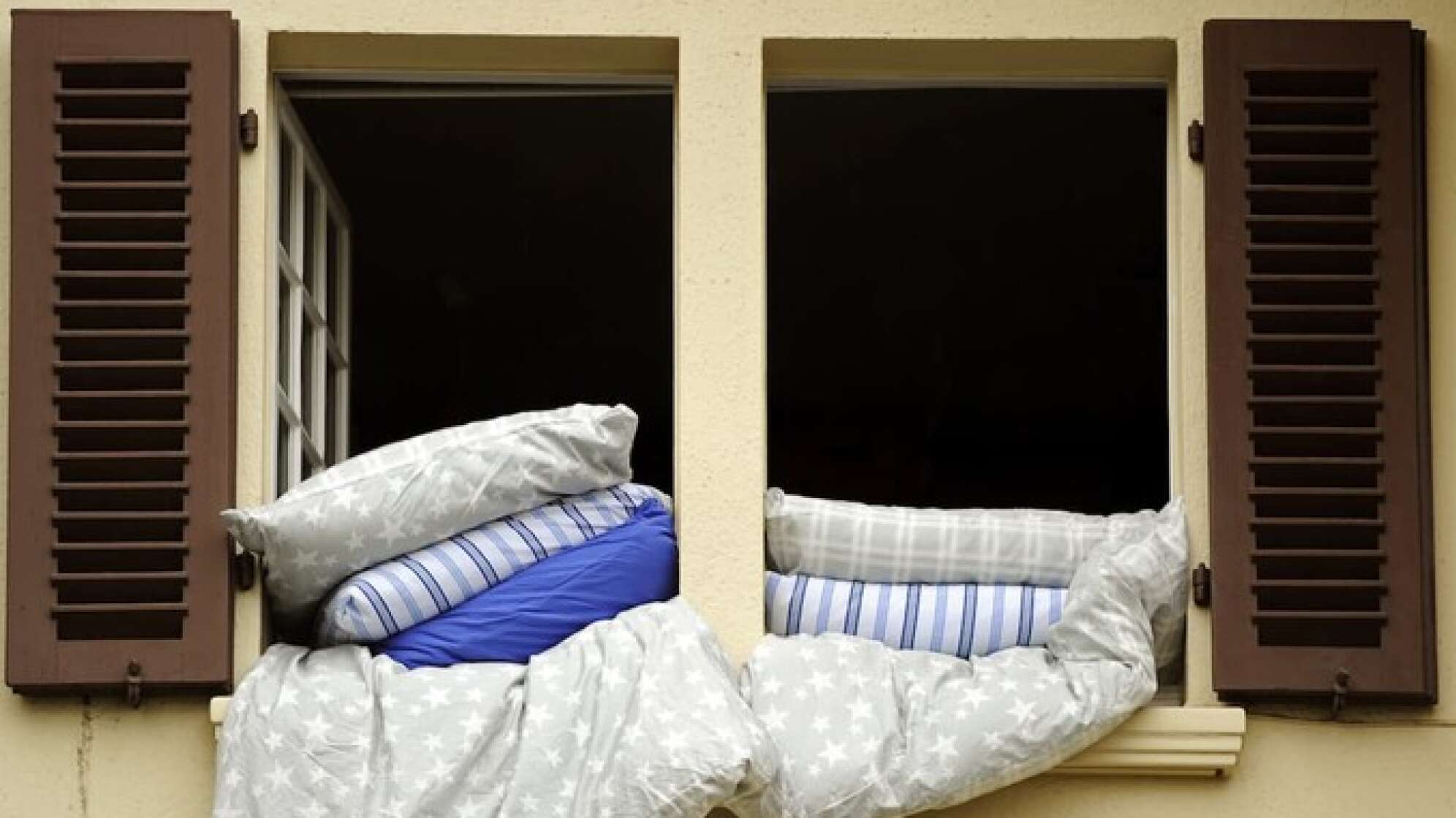 Bettdecke und Kissen lüften am offenen Fenster aus