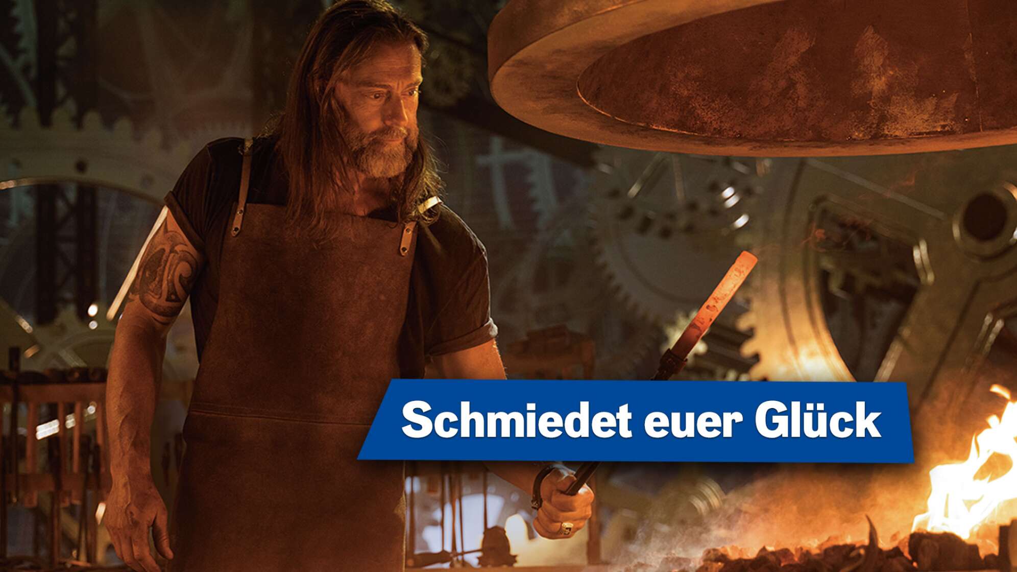 Bild eines Schmieds vor glühenden Kohlen mit Eisenstange in der Hand, Textaufschrift: "Schmiedet euer Glück"