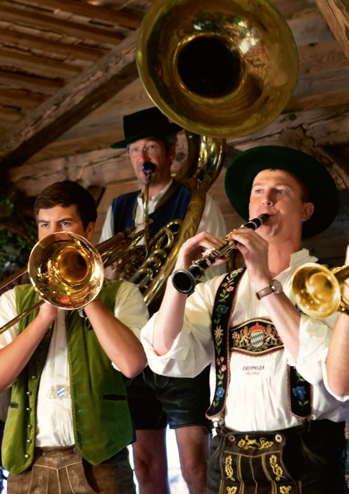 Ein paar Musiker spielen Blasinstrumente in bayerischem Kostüm