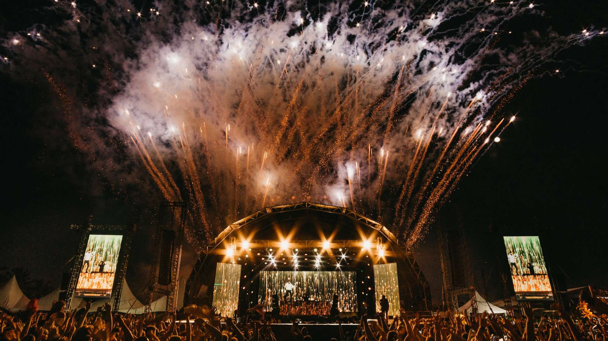 Ein Bild eines Open Air Konzerts im Dunkeln mit großem Feuerwerk im Hintergrund