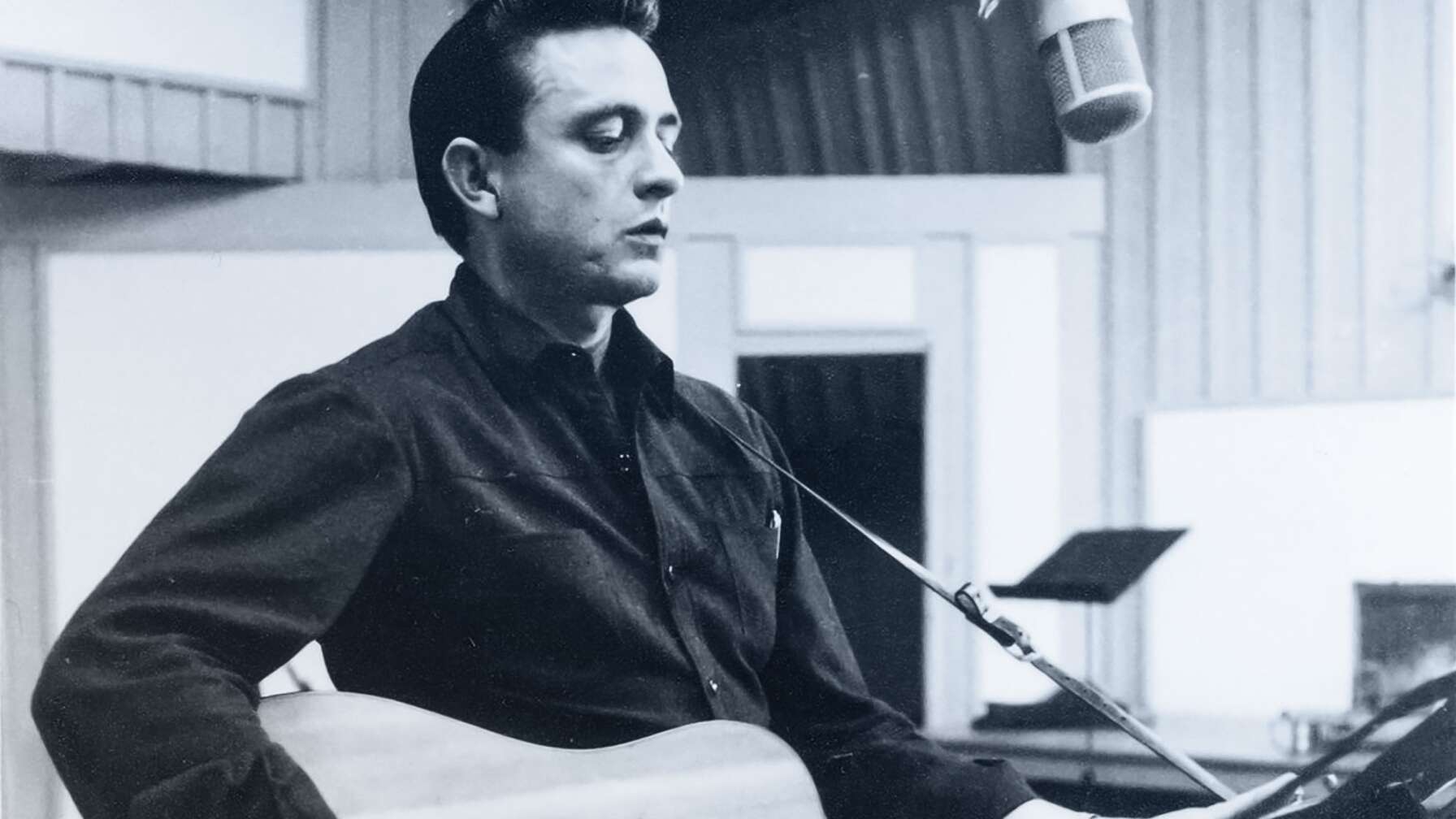 Johnny Cash mit seiner Akustik-Gitarre in einem Studio.