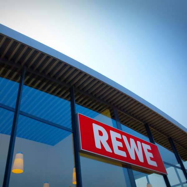 Bild einer REWE Filiale mit großem REWE Logo an einer Glasfassade