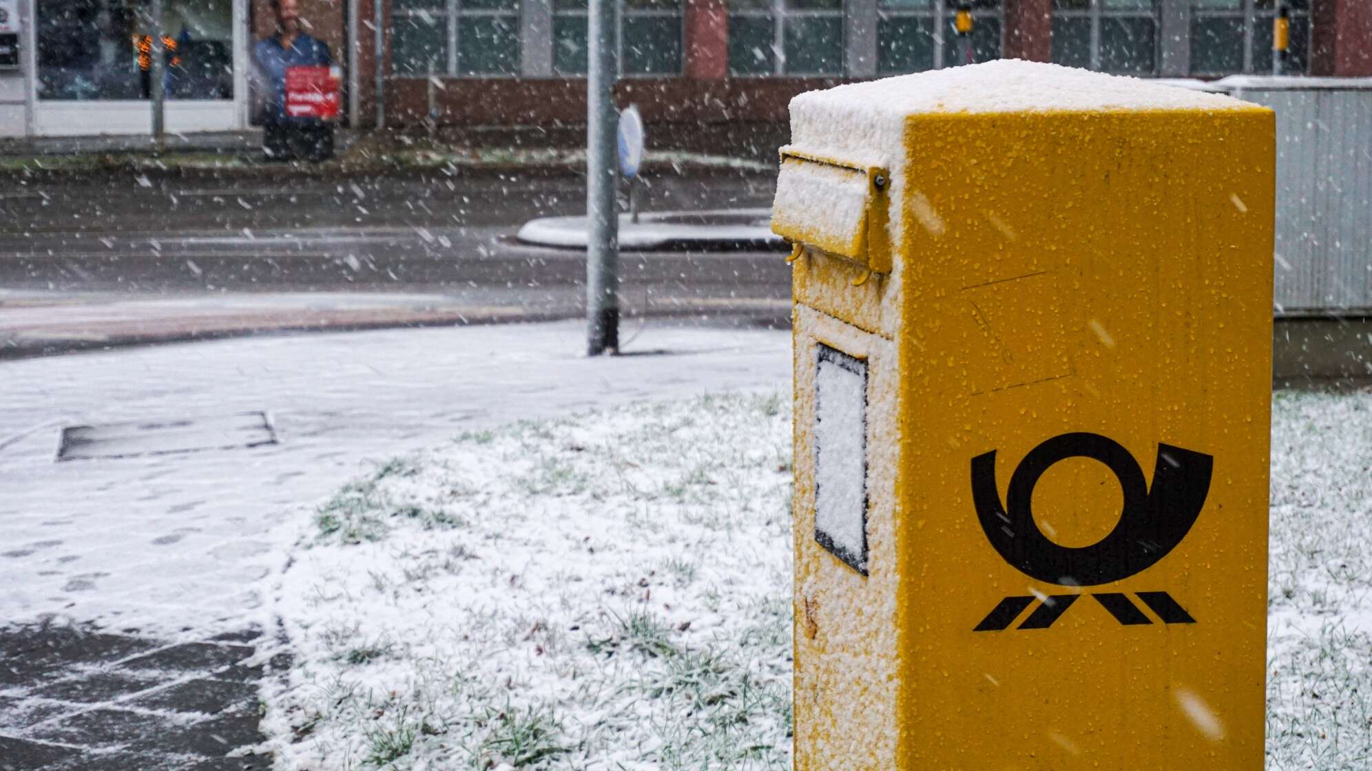 Ein gelb-schwarzer Briefkasten im Schnee