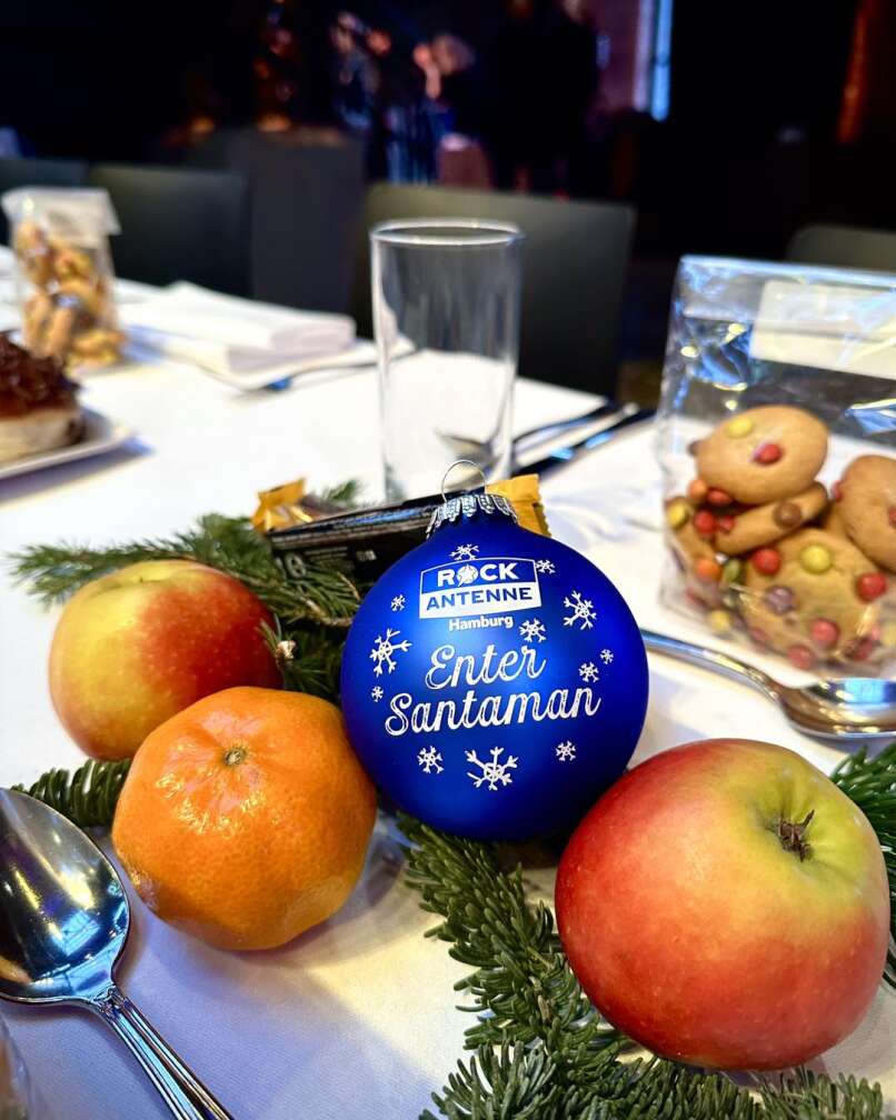 Eine ROCK ANTENNE Hamburg Weihnachtskugel auf dem Tisch mit Mandarinen und Äpfeln