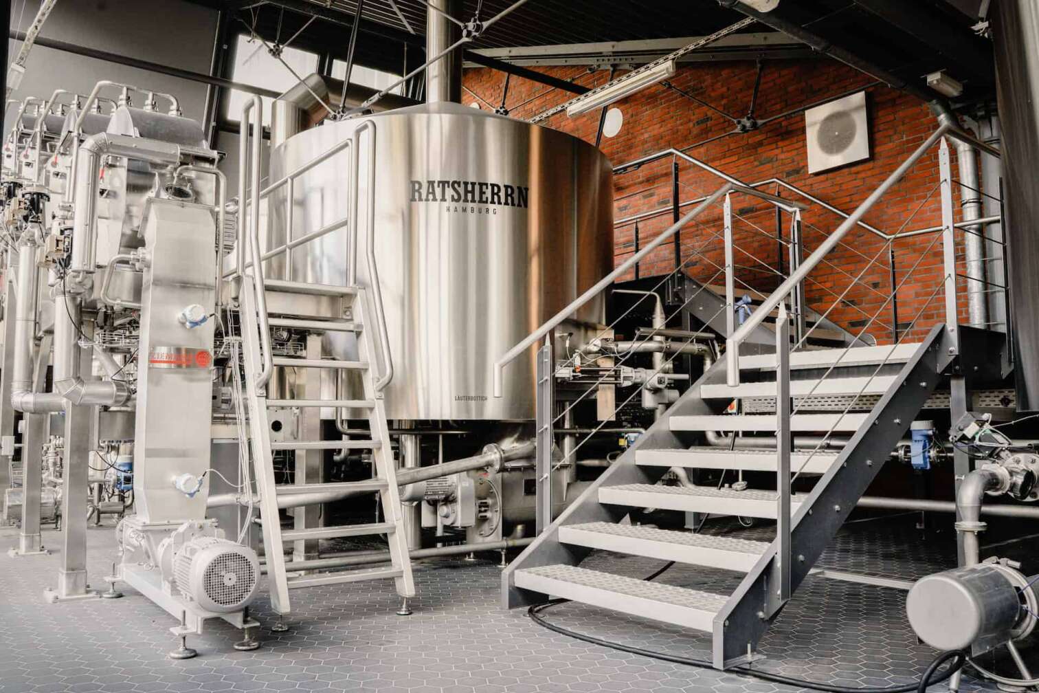 Bild aus dem Inneren der Hamburger Brauerei Ratsherrn im Rahmen einer Brauereiführung, zu sehen sind Kessel und Treppen in einem roten Backsteingebäude