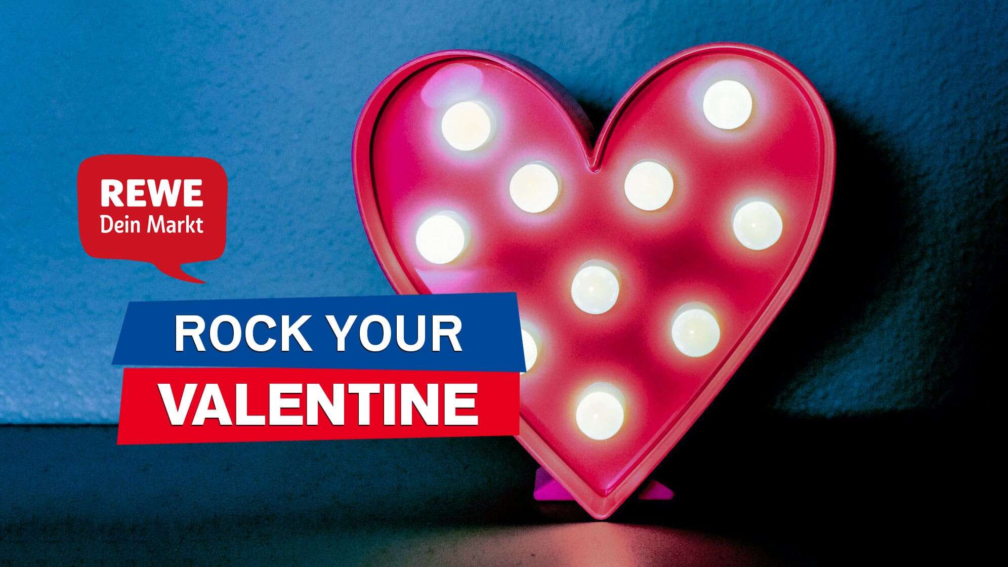 Bild eines roten Herzaufstellers mit runden Glühbirnen, dazu Text - ROCK YOUR VALENTINE - und das REWE Logo
