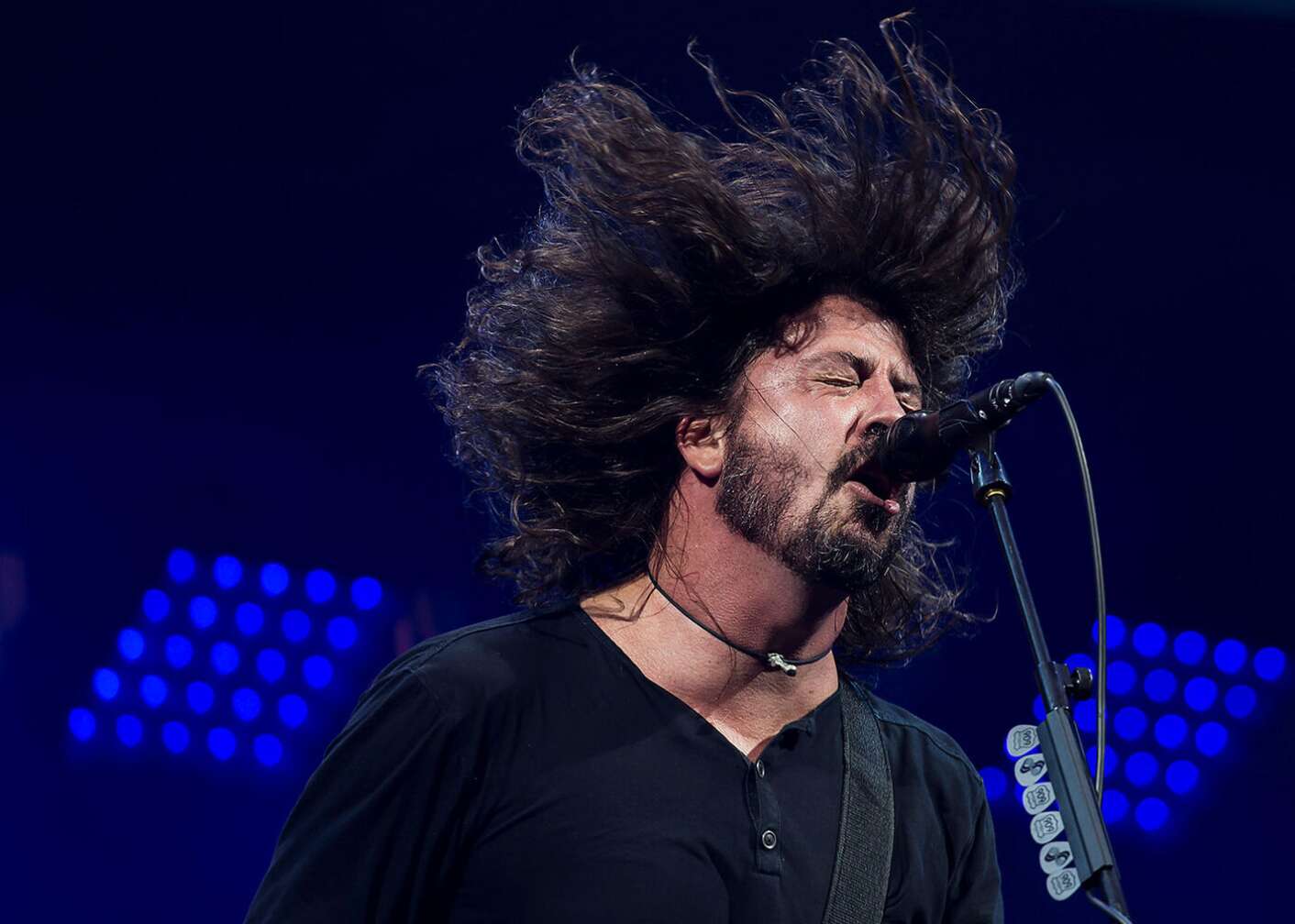 Dave Grohl schreit in ein Mikrofon mit hochgeschleuderten Haaren