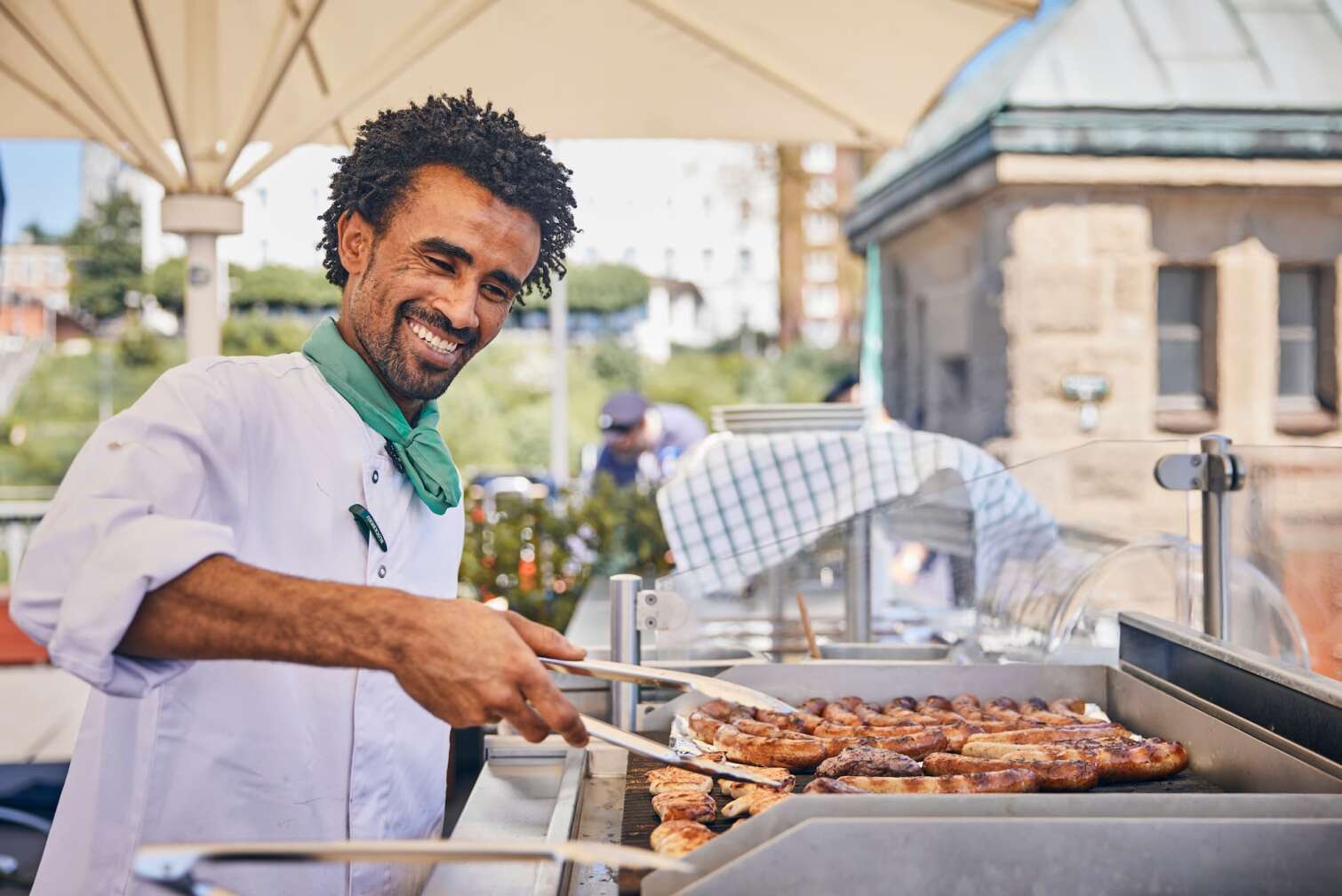 Grillmeister steht am BLOCKBRÄU Grill auf der Hafenterrasse und lächelt in die Kamera