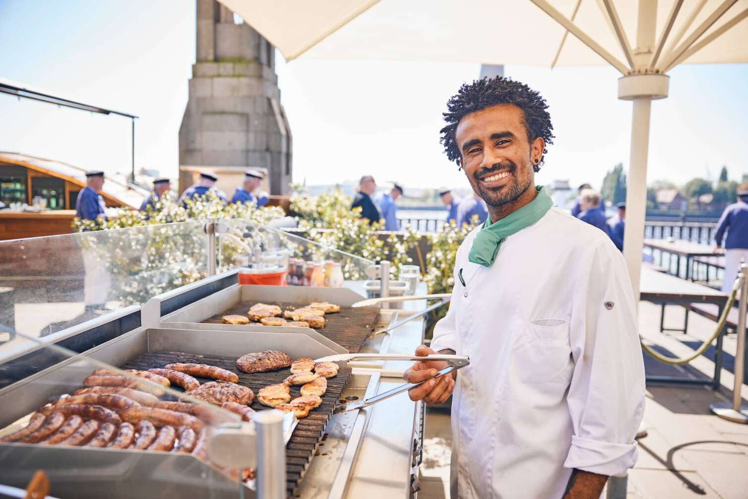 Grillmeister steht am BLOCKBRÄU Grill auf der Hafenterrasse und lächelt in die Kamera