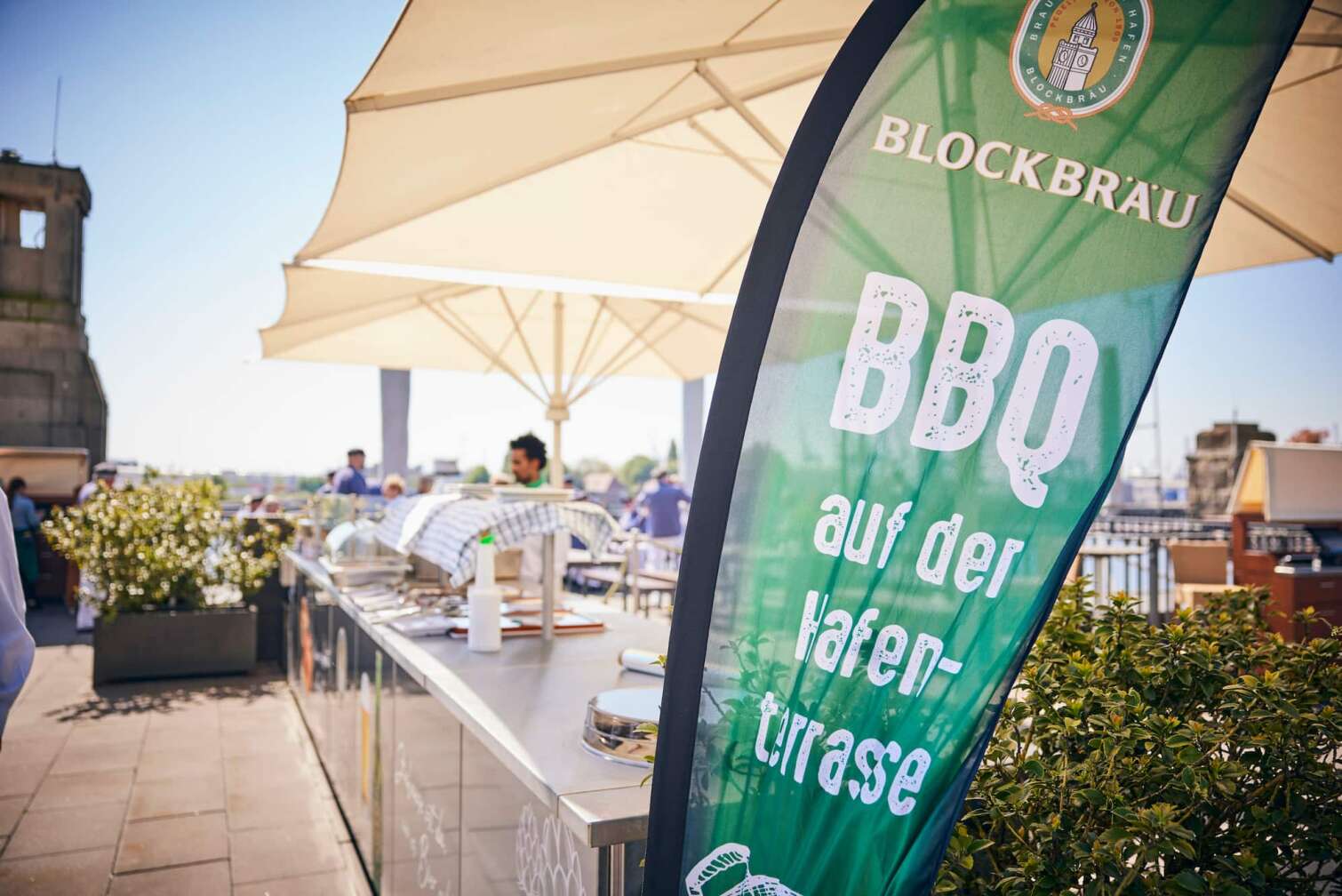 Bild von der BLOCKBRÄU Hafenterrasse, im Hintergrund der Hafen, im Vordergrund ein Werbebanner von Blockbräu