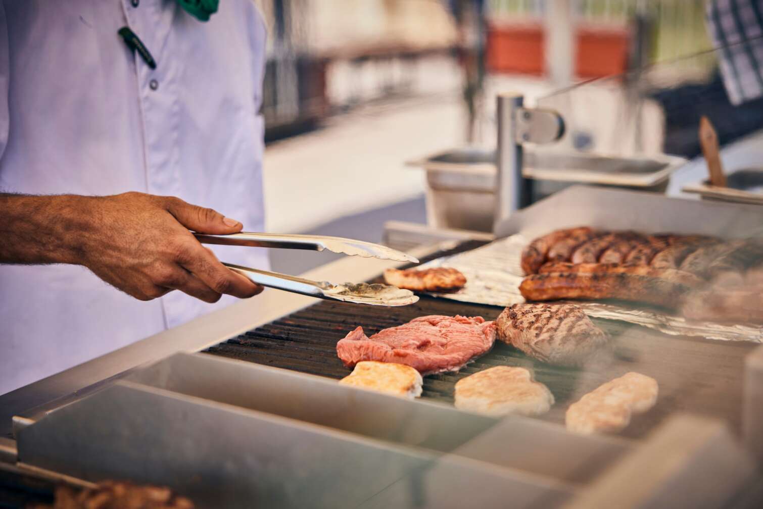 Verschiedene Grillgut Gegenstände (Burgerpatties, Steaks und Würstchen) liegen auf einem Grillrost