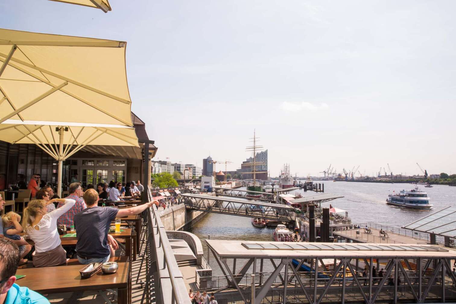 Die Dachterrasse des BLOCKBRÄU, der Brauerei im Hamburger Hafen; im Hintergrund verschwommen die Umrisse der Elbphilharmonie und des Hafens