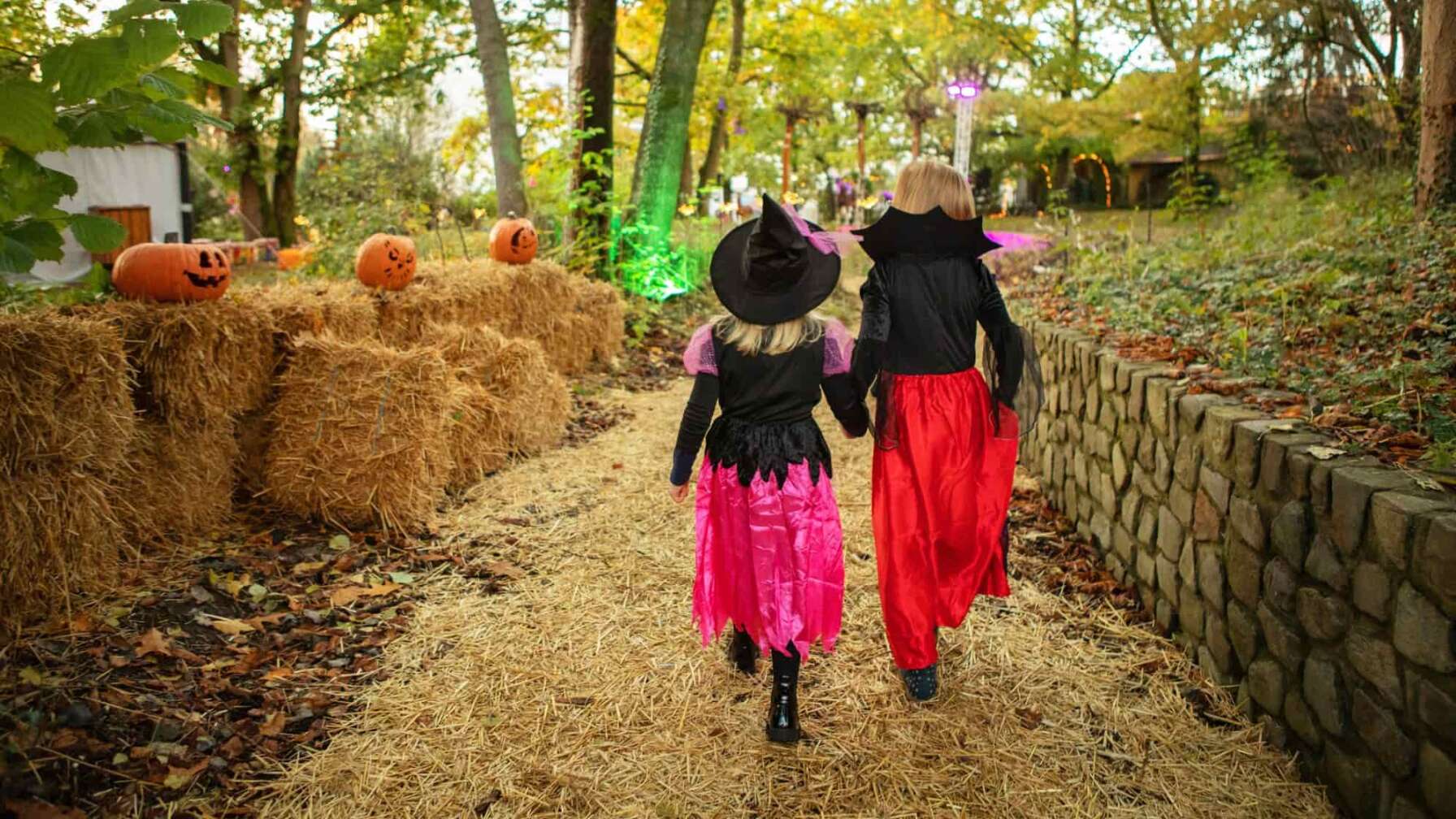 Zwei als Hexen verkleidete Personen, eine Frau und ein Kind, laufen gemeinsam durch ein Strohballen Labyrinth im Heide Park Resort
